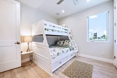 Bright and airy bunk room perfect for families or friends, featuring cozy beds, soft lighting, and coastal touches. A fun yet relaxing space with plenty of room to unwind after a sun-filled day by the beach!