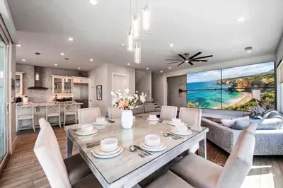 Gather in this bright, open-concept living space featuring a stylish dining area, modern kitchen, and cozy lounge with large TV. Elegant décor, ample seating, and natural light create the perfect setting for meals, relaxation, and memorable stays!