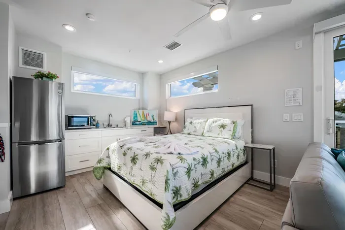 Unwind in this bright and airy bedroom featuring a plush bed, coastal-inspired décor, and natural light throughout. With added convenience of a mini fridge and cozy seating, it’s the perfect private retreat after a relaxing beach day!