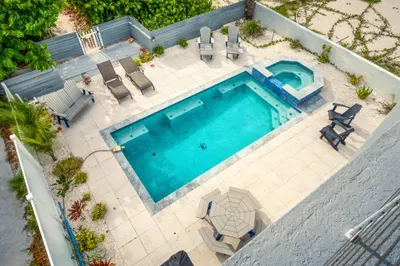 Relax in a private pool with a connected spa, surrounded by lush landscaping and lounge chairs — perfect for family fun or peaceful soaking.