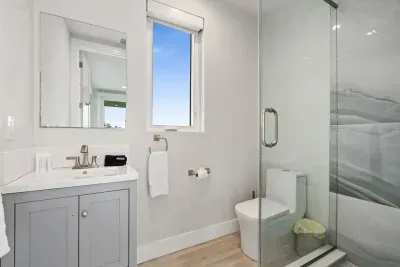 Fresh and modern bathroom featuring a glass shower, bright vanity, and natural light — offering comfort and style for every guest.