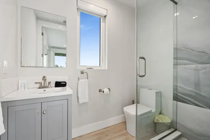 Fresh and modern bathroom featuring a glass shower, bright vanity, and natural light — offering comfort and style for every guest.