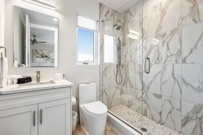 Enjoy a private ensuite with elegant marble finishes, a glass walk-in shower, and modern vanity for a spa-like experience.