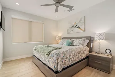 A stylish queen bedroom with soft lighting, ceiling fan, and relaxing décor — perfect for ensuring every guest has their own private oasis.
