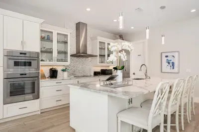 Step into a bright and stylish gourmet kitchen featuring sleek quartz countertops, stainless steel double ovens, and a stunning island with seating for four. The open layout invites conversation while cooking, making it the perfect gathering spot for