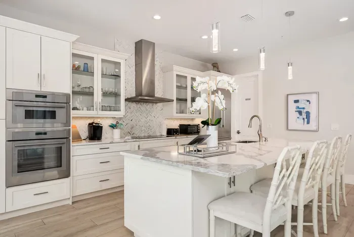 Step into a bright and stylish gourmet kitchen featuring sleek quartz countertops, stainless steel double ovens, and a stunning island with seating for four. The open layout invites conversation while cooking, making it the perfect gathering spot for