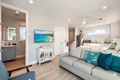 Relax in this cozy living space featuring plush seating, coastal décor, and a large TV for unwinding. Bright and inviting, it offers the perfect spot to recharge after a day at the beach or gather for a movie night with family and friends!