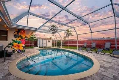 Pool area with lounge chairs, string lights, and dart board.
