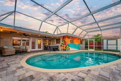 Screened in lanai with heated pool, hot tub, patio furniture, and string lights.