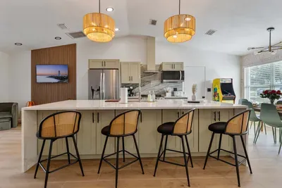 A close-up view of elegant bar stools with rattan backs, perfectly complementing the modern kitchen island. The sleek design combines comfort and style, inviting guests to enjoy casual meals or morning coffee in a chic, welcoming atmosphere.