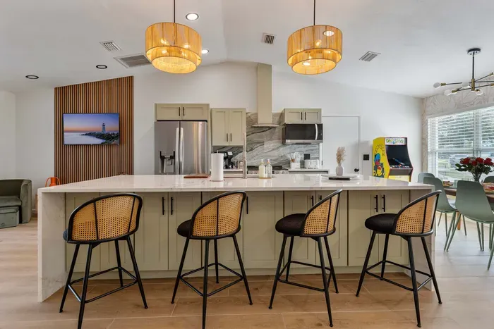 A close-up view of elegant bar stools with rattan backs, perfectly complementing the modern kitchen island. The sleek design combines comfort and style, inviting guests to enjoy casual meals or morning coffee in a chic, welcoming atmosphere.