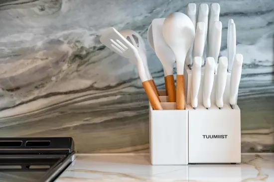 A modern utensil holder stands elegantly on the countertop, featuring a mix of minimalist white and warm wooden utensils. The sleek design perfectly complements the stunning marble backdrop, adding a touch of sophistication to the kitchen.