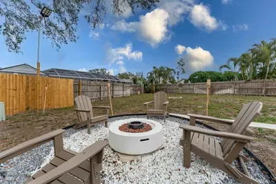 This inviting view showcases the fire pit area from a slightly elevated angle, highlighting the easy access from the house. The fenced-in yard provides a tranquil atmosphere, ideal for relaxation and socializing in the open air.