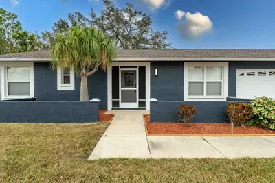 A detailed view of the welcoming front door framed by large windows that flood the space with natural light. The neat flower beds flanking the entrance enhance the home's curb appeal, inviting guests to step inside.