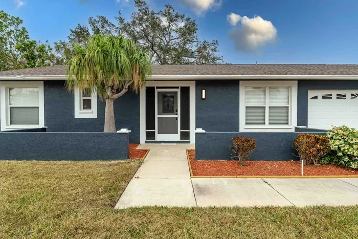 A detailed view of the welcoming front door framed by large windows that flood the space with natural light. The neat flower beds flanking the entrance enhance the home's curb appeal, inviting guests to step inside.