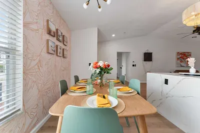 A close-up of the dining table highlights a thoughtfully arranged place setting, showcasing modern glassware and bright yellow napkins. The centerpiece of fresh flowers brings a touch of nature indoors, creating an inviting atmosphere for shared meal