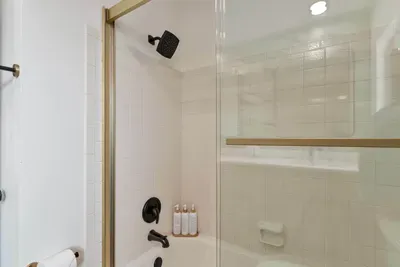 A stunning shower area featuring beautiful marble tiles and a glass enclosure that highlights the luxurious design. Soft light filters through the window, creating an inviting space for a refreshing shower experience.