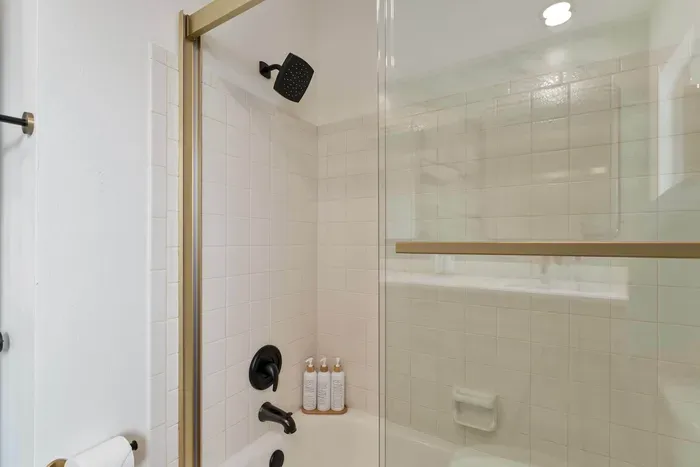 A stunning shower area featuring beautiful marble tiles and a glass enclosure that highlights the luxurious design. Soft light filters through the window, creating an inviting space for a refreshing shower experience.