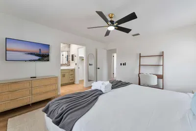 A spacious layout captures the essence of contemporary living, with a cozy bed and tasteful decor. A wall-mounted TV offers entertainment options, and a chic bookshelf adds character to the space