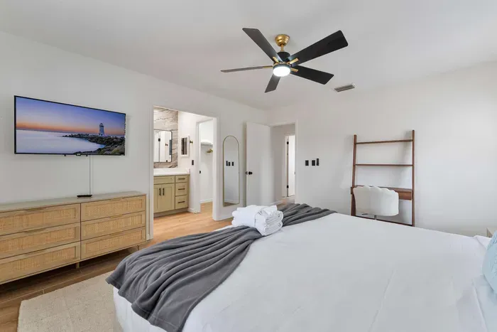 A spacious layout captures the essence of contemporary living, with a cozy bed and tasteful decor. A wall-mounted TV offers entertainment options, and a chic bookshelf adds character to the space