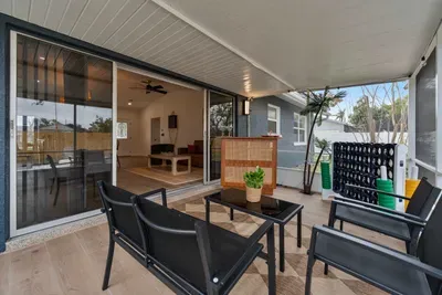 A charming outdoor space featuring a comfy seating arrangement alongside a large Connect Four game. The chic bar table adds an element of fun, while the view of the lush backyard creates a perfect setting for relaxation and entertainment