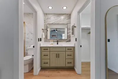 A sleek bathroom corner featuring elegant bottles labeled for body wash, shampoo, and conditioner, all neatly arranged on a wooden tray.