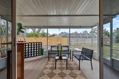 This inviting image highlights a screened-in patio, complete with comfortable seating and a small coffee table. The natural light filtering in, combined with lush greenery from the outside, creates a serene retreat perfect for enjoying warm evenings