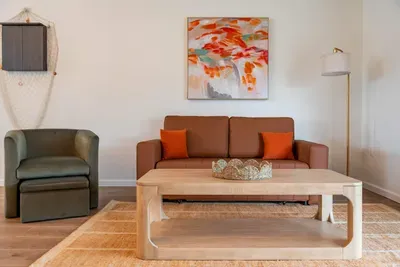 A beautifully decorated entertainment area highlighting a stunning piece of coastal art on the wall. The sleek TV setup and soft furnishings create a sophisticated space, inviting guests to enjoy both comfort and style.