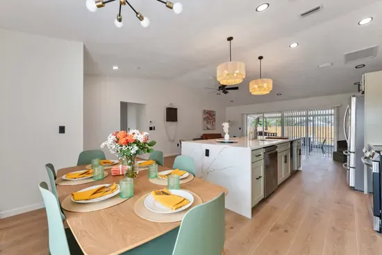 A well-lit dining area featuring a stylish table surrounded by chic chairs, perfect for gatherings. The eye-catching wall design paired with natural light streaming through the window creates a warm, inviting space ideal for both casual meals.
