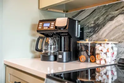 A close-up of the kitchen area showcases a well-organized countertop with a high-end coffee maker, perfect for brewing morning treats. The intricate marble backsplash enhances the overall design, creating a functional yet elegant cooking space.