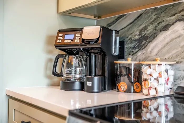 A close-up of the kitchen area showcases a well-organized countertop with a high-end coffee maker, perfect for brewing morning treats. The intricate marble backsplash enhances the overall design, creating a functional yet elegant cooking space.