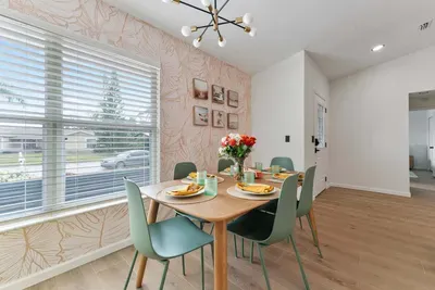 An inviting dining setup featuring a beautifully crafted wooden table adorned with stylish place settings. Vibrant yellow napkins complement the elegant glassware, while a cheerful bouquet of roses adds a pop of color.