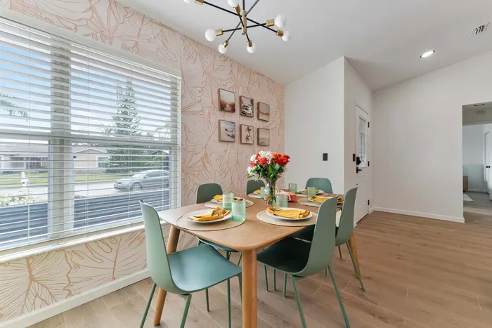 An inviting dining setup featuring a beautifully crafted wooden table adorned with stylish place settings. Vibrant yellow napkins complement the elegant glassware, while a cheerful bouquet of roses adds a pop of color.