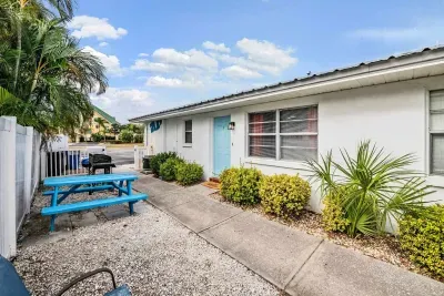 Charming outdoor space with coastal blue accents, picnic seating, and lush tropical greenery. Perfect for morning coffee or evening chats, this sunny, beachy courtyard invites you to relax and enjoy the island vibe.