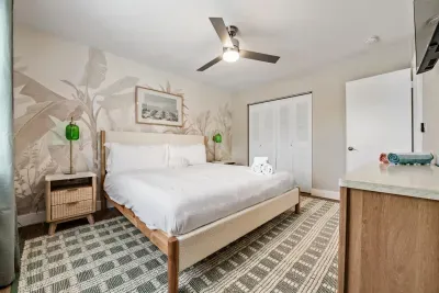 Spacious, tranquil bedroom featuring a plush king bed, soft coastal décor, and a serene mural backdrop. Enjoy ample storage and calming natural light—your perfect retreat for rest and relaxation.