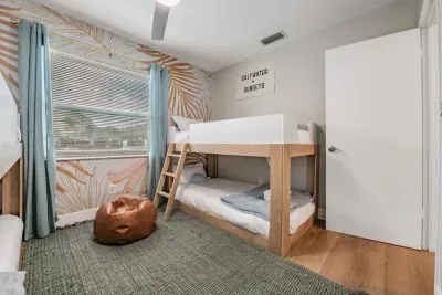 Bright, fun bunk room featuring cozy twin bunks, a stylish accent wall, and soft natural light. Perfect for kids or groups, this inviting space offers comfort, charm, and a relaxed vacation vibe.