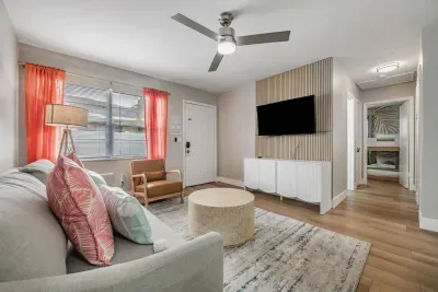Cozy, sunlit living room with vibrant accents, plush seating, and a sleek mounted TV. Enjoy a warm, welcoming space perfect for movie nights, relaxing, and connecting—your ideal home-away-from-home.