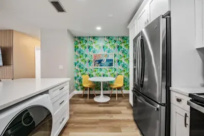Charming dining nook with bold, tropical wallpaper and bright modern seating. Nestled beside the sleek kitchen, it’s the perfect spot for morning coffee, quick bites, or relaxed conversations.