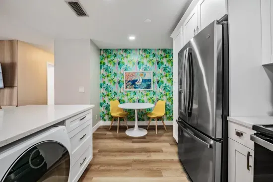 Charming dining nook with bold, tropical wallpaper and bright modern seating. Nestled beside the sleek kitchen, it’s the perfect spot for morning coffee, quick bites, or relaxed conversations.