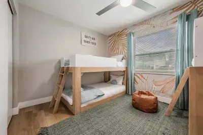 Cozy bunk room with stylish wood-frame beds, playful accent walls, and soft natural light. Perfect for kids or groups, this fun, comfortable space creates the ideal spot to relax and recharge.