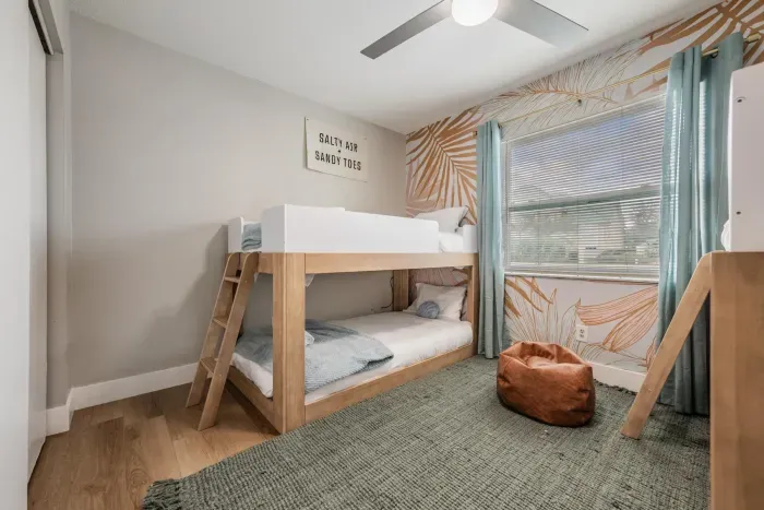 Cozy bunk room with stylish wood-frame beds, playful accent walls, and soft natural light. Perfect for kids or groups, this fun, comfortable space creates the ideal spot to relax and recharge.