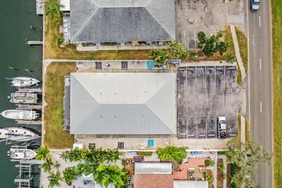 Aerial view of this waterfront property showcasing prime canal access, boat slips, and convenient parking. Enjoy peaceful coastal living just steps from the water—your ideal island getaway awaits.