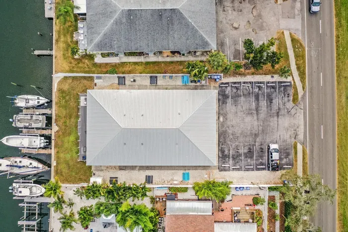 Aerial view of this waterfront property showcasing prime canal access, boat slips, and convenient parking. Enjoy peaceful coastal living just steps from the water—your ideal island getaway awaits.