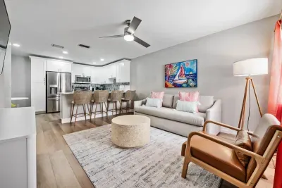 Bright, modern living space with a sleek kitchen, plush seating, and warm décor. Enjoy stainless appliances, a cozy lounge area, and stylish touches throughout—perfect for relaxing or gathering in comfort and style.