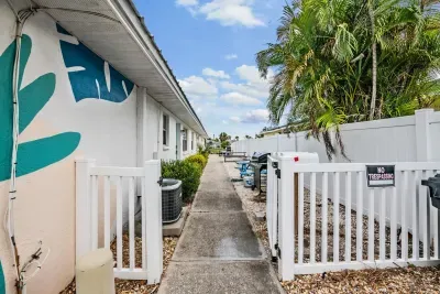 Welcoming gated walkway lined with tropical greenery and vibrant mural accents. This bright, breezy path leads you into a peaceful coastal escape—offering privacy, charm, and a true vacation vibe from the moment you arrive.