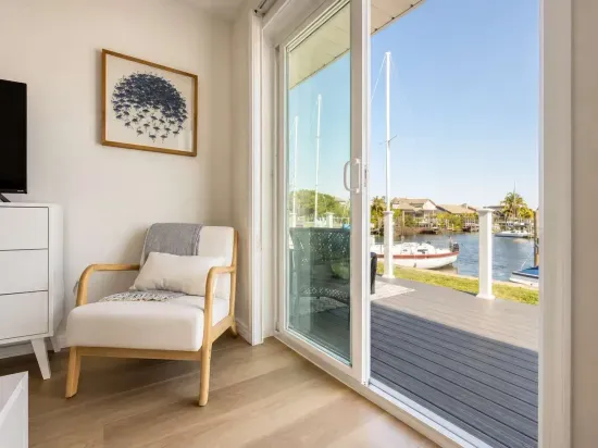 Peaceful waterfront view from a cozy sitting nook with modern décor and sliding glass doors leading to the deck. Perfect for morning coffee or evening sunsets overlooking the canal and passing boats.