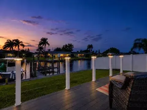 Twilight canal-side deck with glowing post-cap lights, peaceful waterfront views, and cozy outdoor seating. Unwind by the water, watch boats pass by, and enjoy the calm coastal atmosphere after sunset.