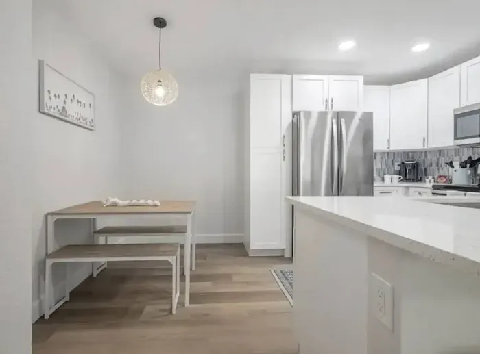 Charming dining nook with a modern wooden table and bench seating, illuminated by a stylish pendant light. Nestled beside the kitchen, it offers a cozy, contemporary space perfect for enjoying meals or morning coffee.