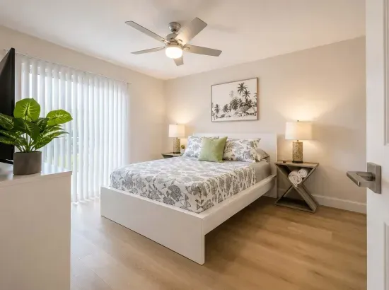 Bright and airy bedroom featuring a plush queen bed, crisp linens, and calming coastal tones. Large windows fill the space with natural light, while modern décor and sleek flooring create a relaxing, contemporary retreat.