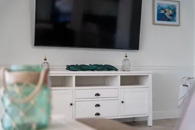 Relax and unwind in the spacious living room, complete with a large flat-screen TV for all your entertainment needs. Whether you're catching up on your favorite shows, streaming movies, or enjoying a family movie night, this cozy space has everything